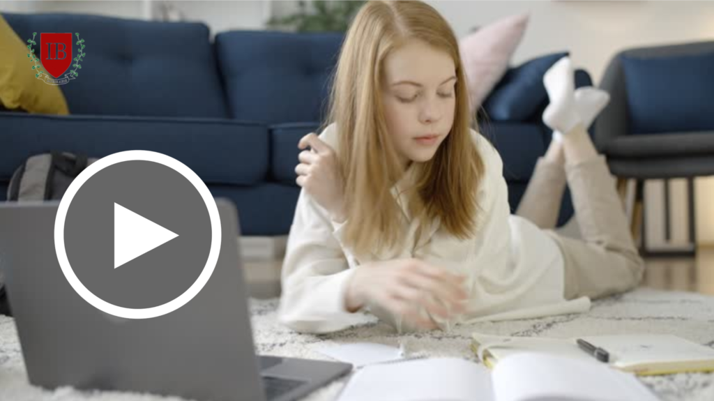 A student with light brown hair lies on a carpeted living room floor, propped up on her elbows while writing in an open notebook, with a laptop and backpack nearby and a navy-blue couch in the background. The IvyBoost crest logo appears in the top left corner.
